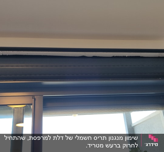 תריס גלילה אפור מותקן מעל חלון זכוכית